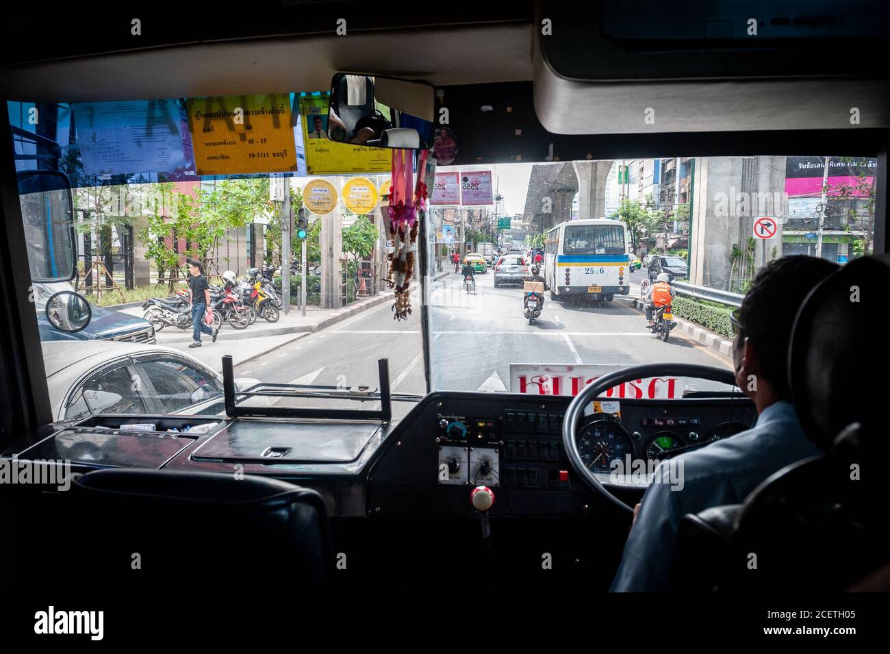 Una foto che guarda attraverso la finestra frontale di un tipico autobus pubblico thailandese che guida lungo Sukhumvit Rd. Bangkok, Thailandia. Foto Stock