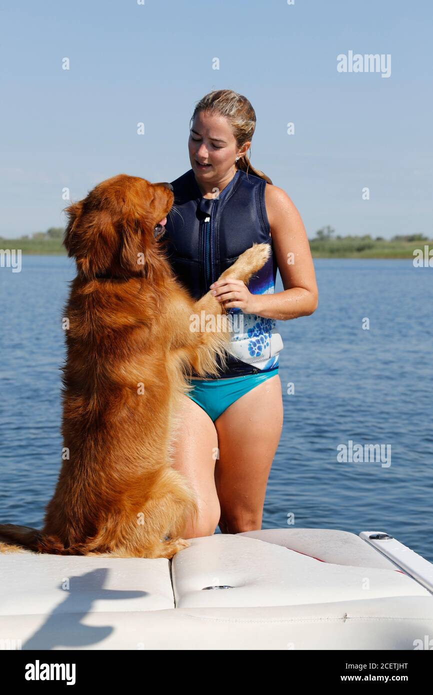 Giovane donna con un cane grande su una barca. Foto Stock