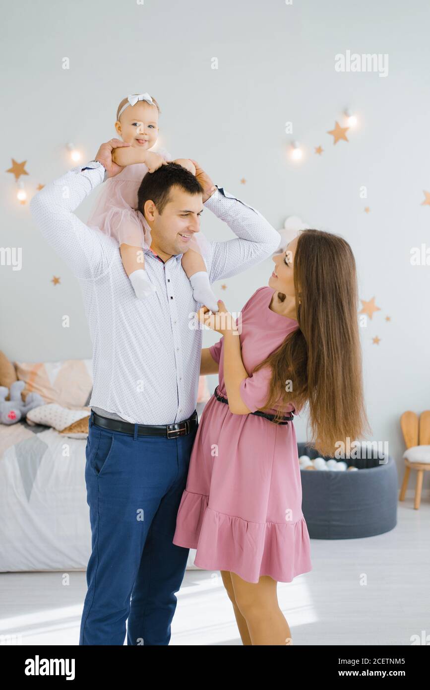 La figlia sorride e rotola sul collo del padre. Mamma felice è in piedi Foto Stock