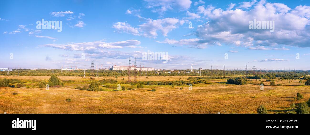 Paesaggio industriale con campi, zona industriale e linea di alimentazione ad alta tensione. Vista panoramica HDR Foto Stock