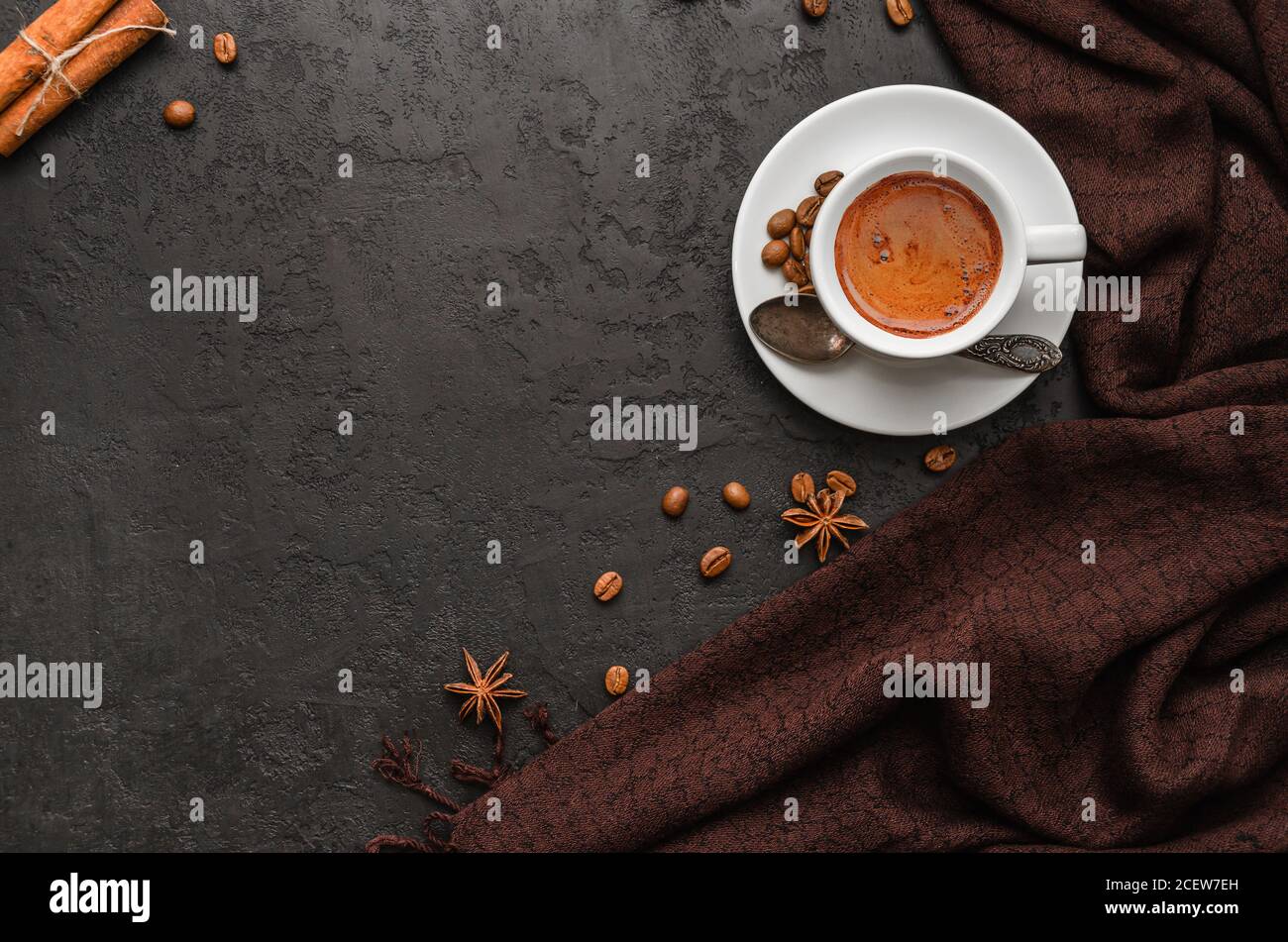 Composizione autunnale. Tazza di caffè, sciarpa di pashmina marrone, chicchi di caffè, bastoncini di cannella su sfondo nero. Umore autunnale. Disposizione piatta. Spazio di copia Foto Stock