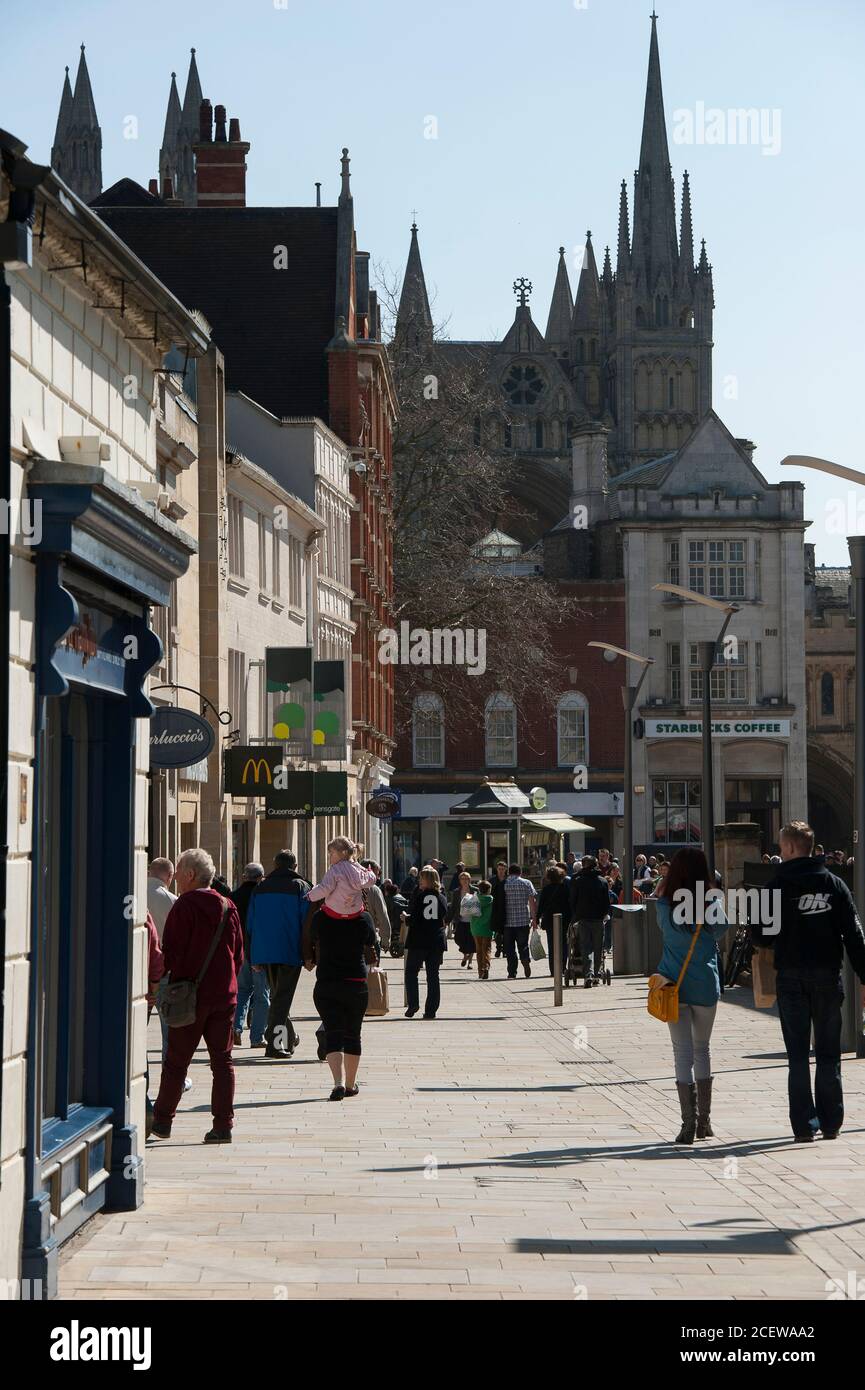 Negozi su una strada a Peterborough con la Cattedrale che sorge sullo sfondo, Cambridgeshire, Inghilterra. Foto Stock