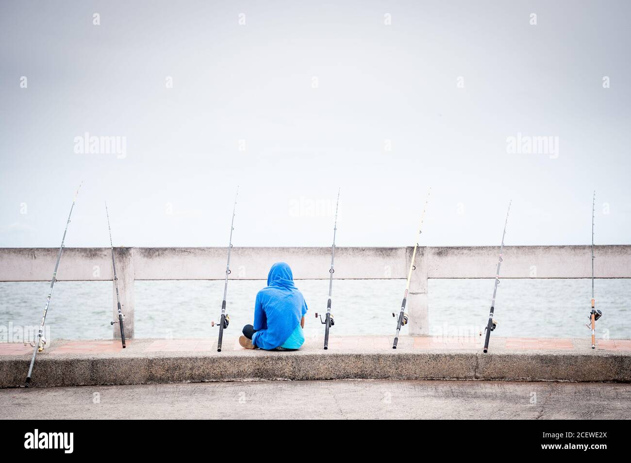 Un pescatore solista si siede in attesa di un boccone in un molo a Bang Saen, vicino Pattaya Thailandia. Foto Stock