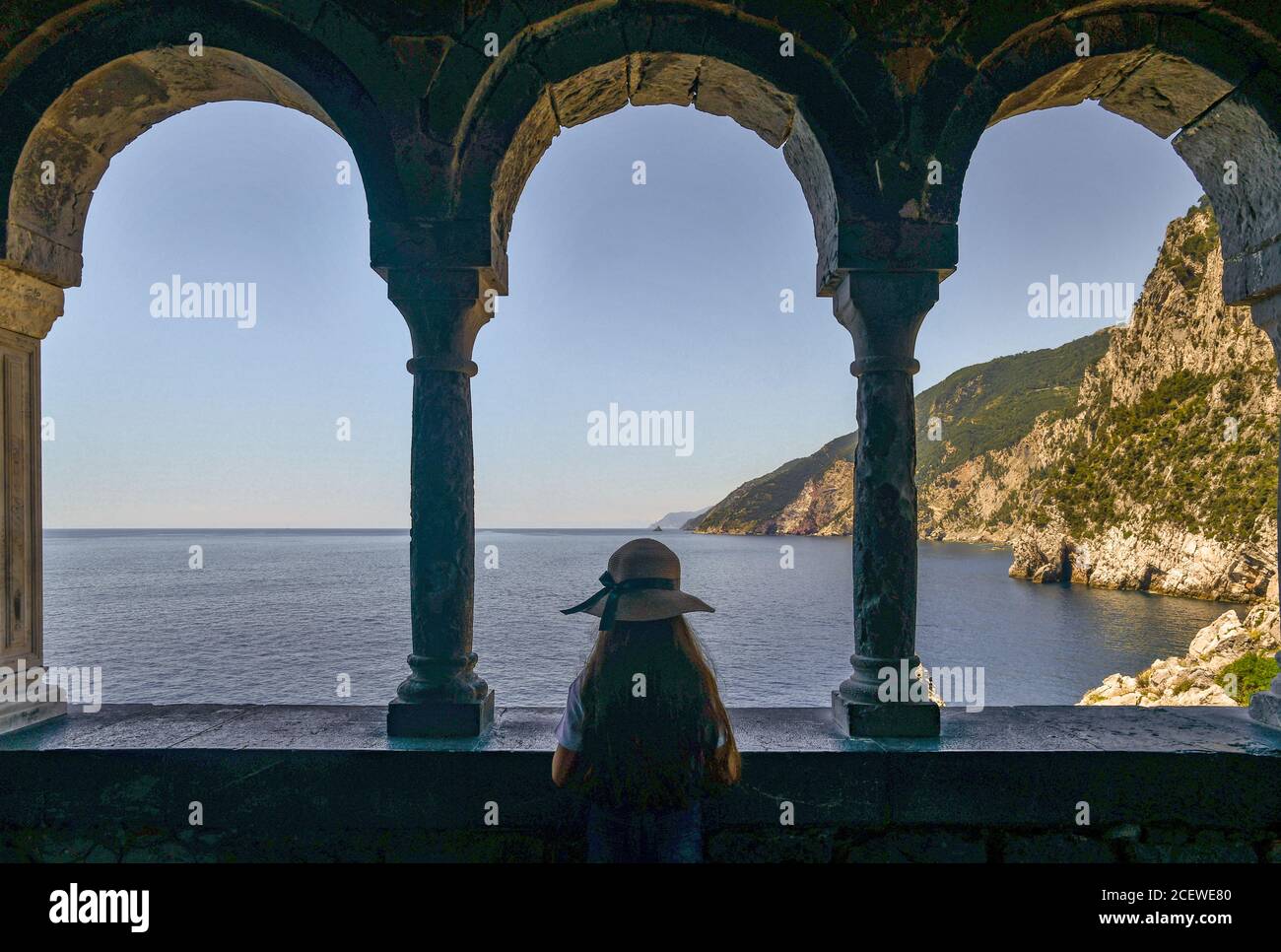Bambina da dietro ammirando il panorama da un porticato della Chiesa di San Pietro nel villaggio di pescatori di Porto Venere, la Spezia, Liguria, Italia Foto Stock