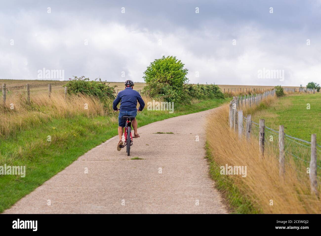 Uomo anziano in bicicletta su collina sul Monarch Trail, Steyning Bowl, South Downs, West Sussex, Regno Unito Foto Stock