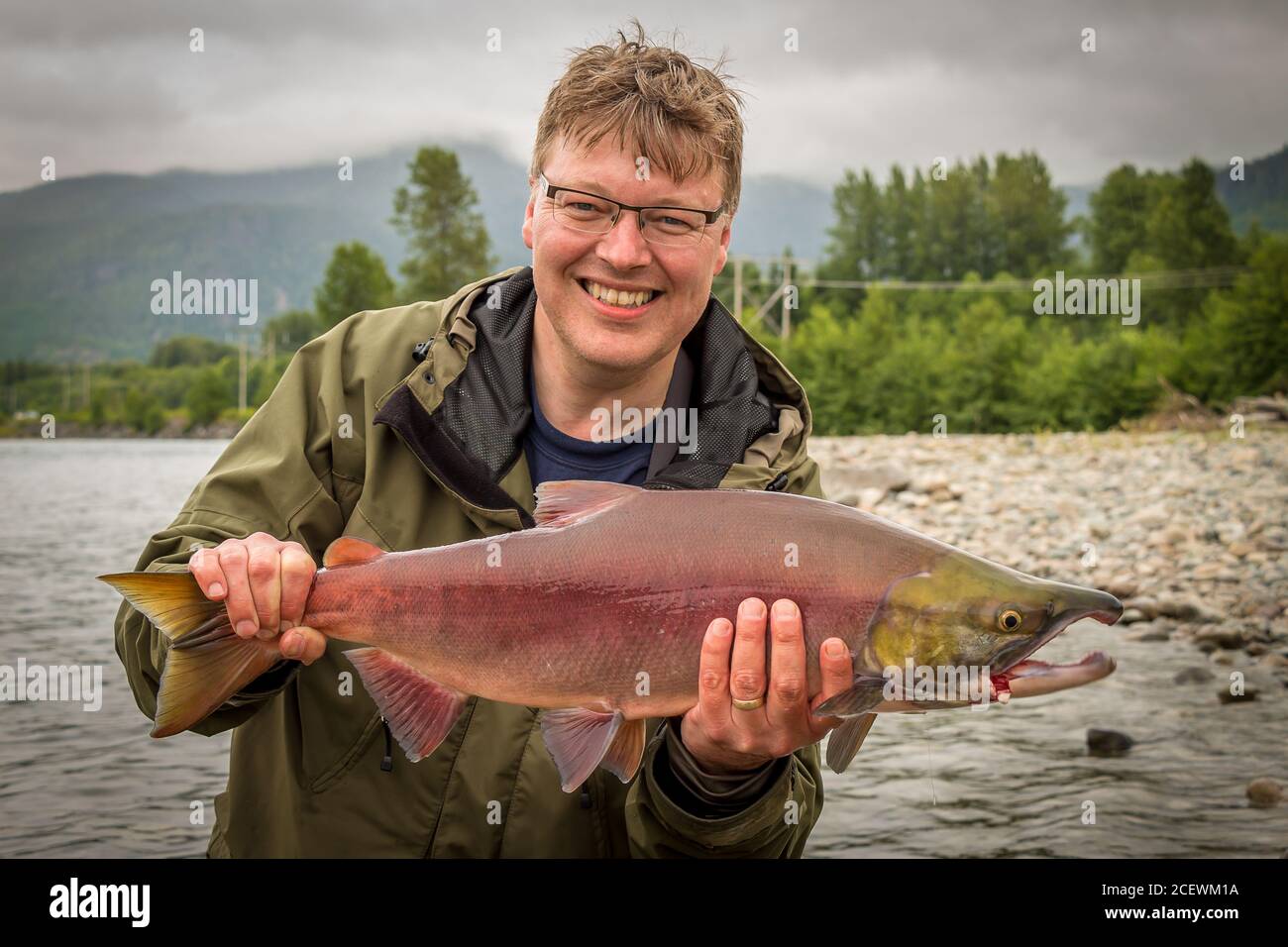 Un felice pescatore che tiene in mano un salmone rosso sockeye, catturato sul fiume kitimat, British Columbia, Canada Foto Stock