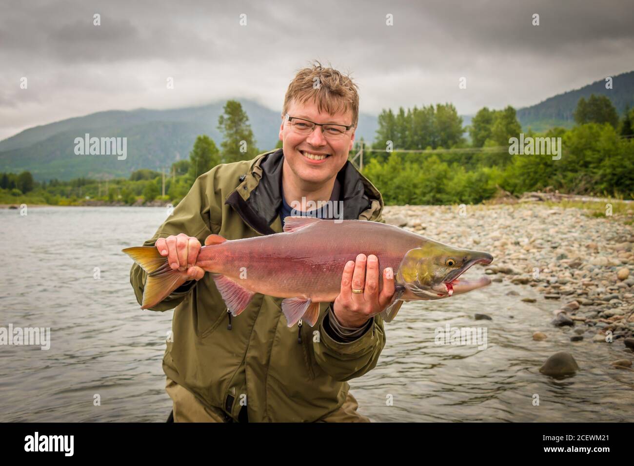 Un felice pescatore che tiene in mano un salmone rosso sockeye, catturato sul fiume kitimat, British Columbia, Canada Foto Stock