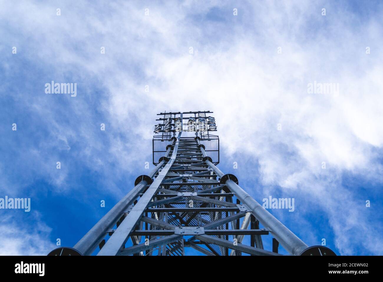 Riflettore a torre in metallo che punta le luci sul campo, cielo blu con alcune nuvole Foto Stock