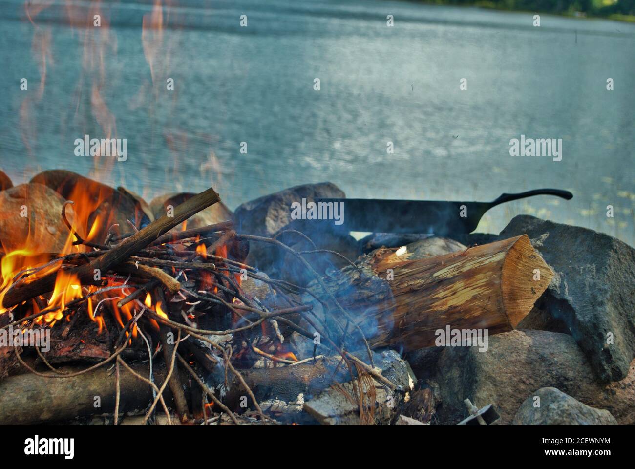 Cucina su una padella di ghisa sopra un fuoco di campo successivo al lago Foto Stock