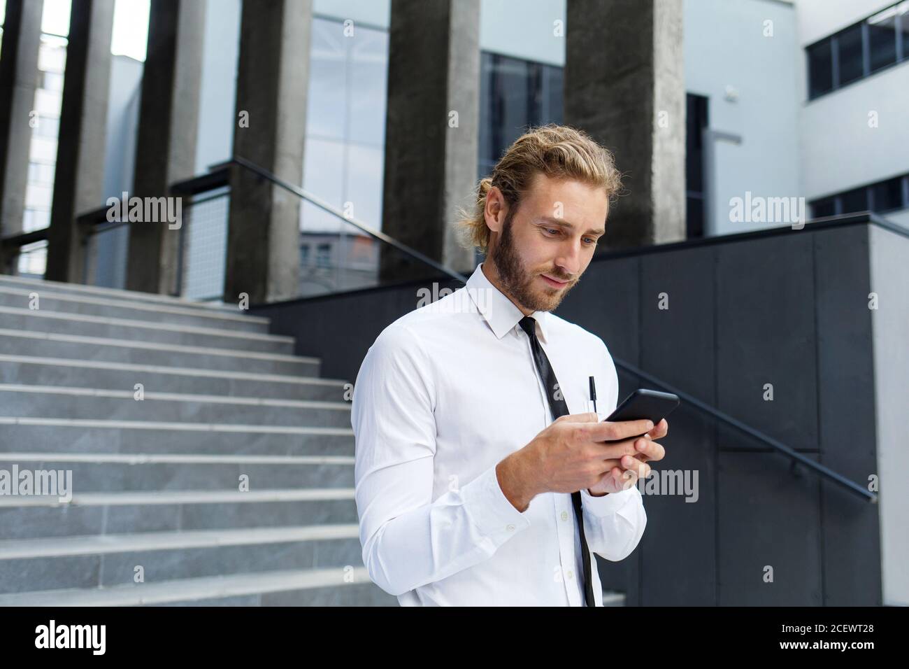 Ritratto Di Un Giovane Imprenditore Di Successo Un Uomo Dai Capelli Ricci In Una Camicia Bianca Con Un Telefono Sullo Sfondo Di Un Moderno Business Center Foto Stock Alamy