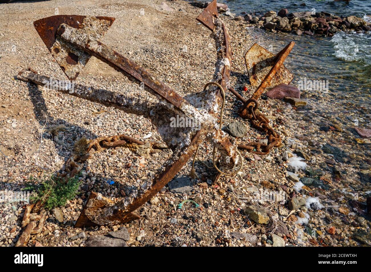 Vecchia ancora arrugginita inutilizzata sulla riva del mare Foto Stock