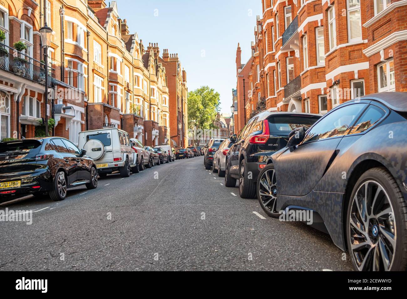 Londra- Via di attraenti case a schiera in mattoni rossi a Chelsea con auto parcheggiate Foto Stock