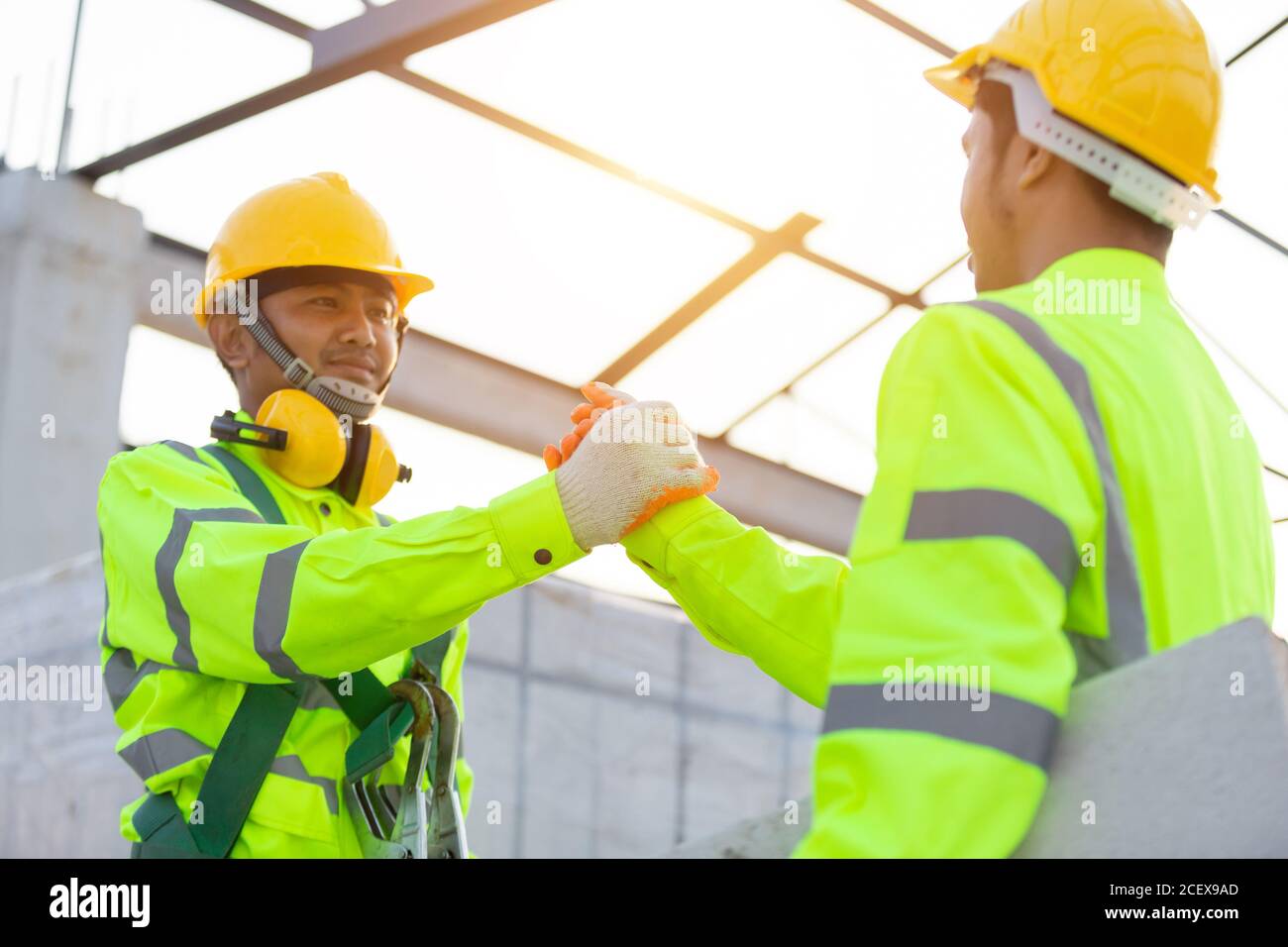 I lavoratori asiatici indossano attrezzature di sicurezza altezza costruzione, lavoro di squadra, partnership, gesto e concetto di persone - primo piano di costruttori mani in guanti di saluto Foto Stock