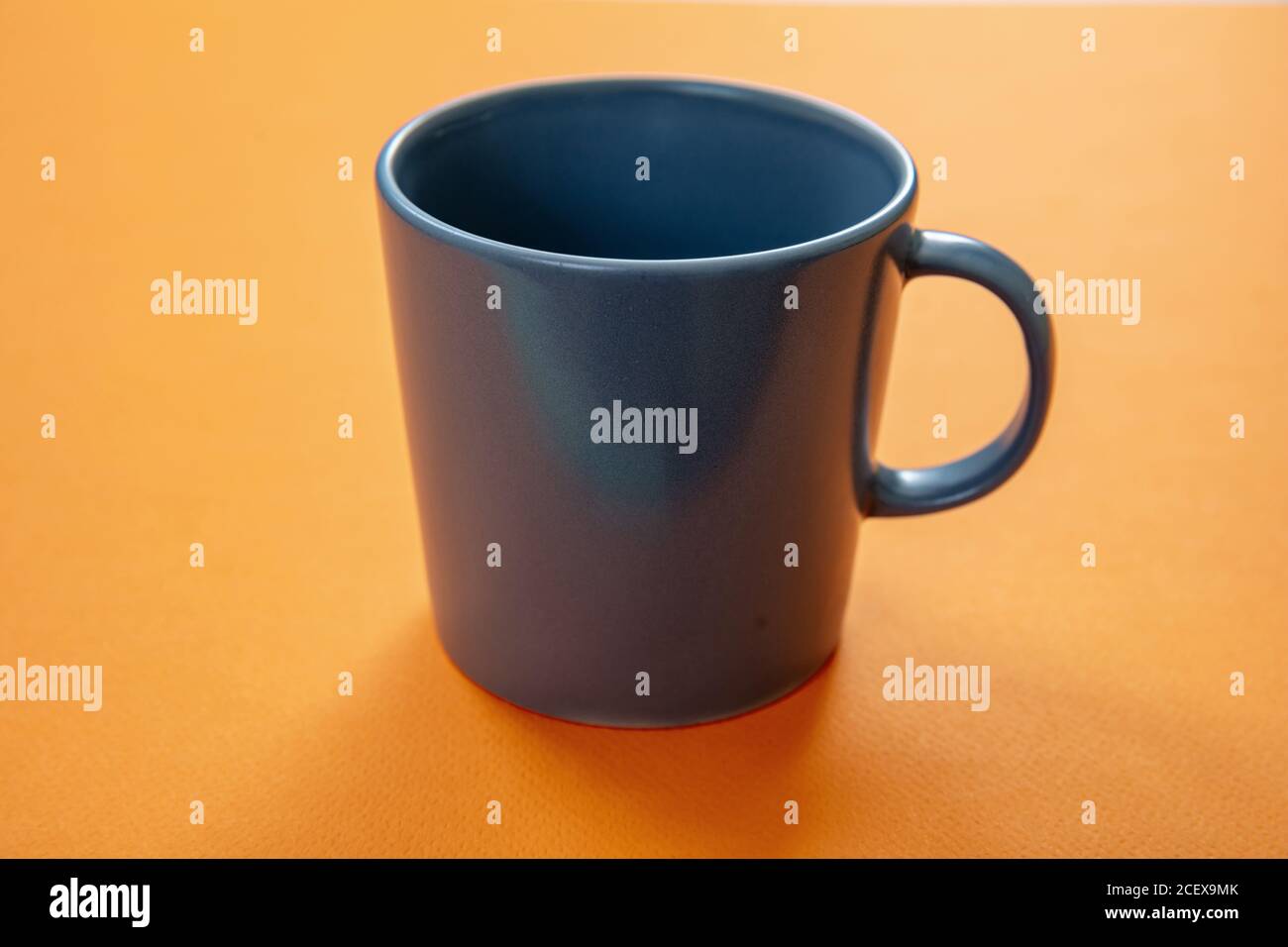 Tazza di caffè su sfondo arancione. Mockup di bevande calde. Tazza vuota di colore grigio con maniglia pubblicità, modello di branding Foto Stock