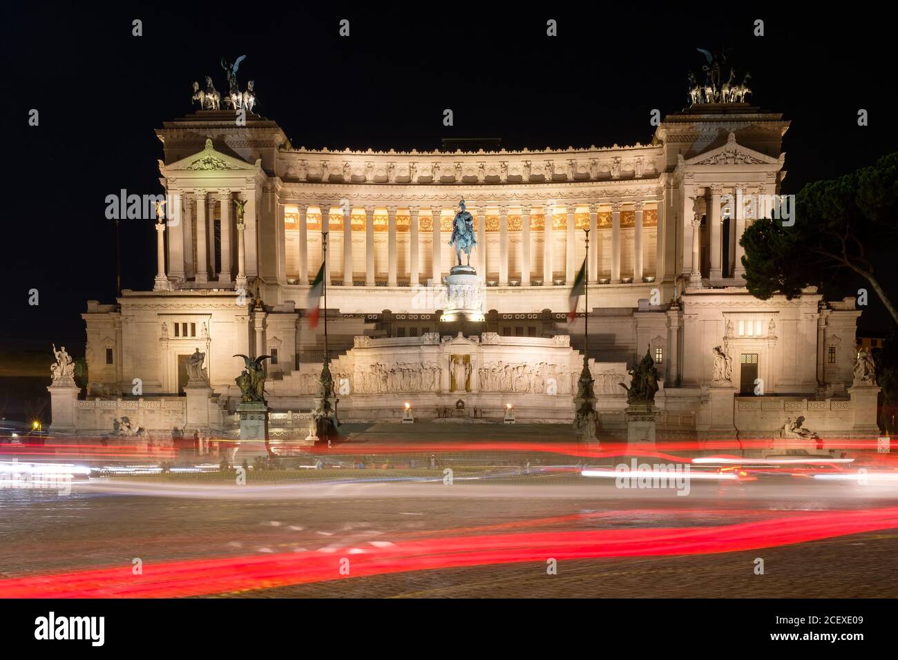 Illuminato il monumento di Vittorio Emanuele II nel centro di Roma di notte con sentieri leggeri dal traffico in transito Foto Stock