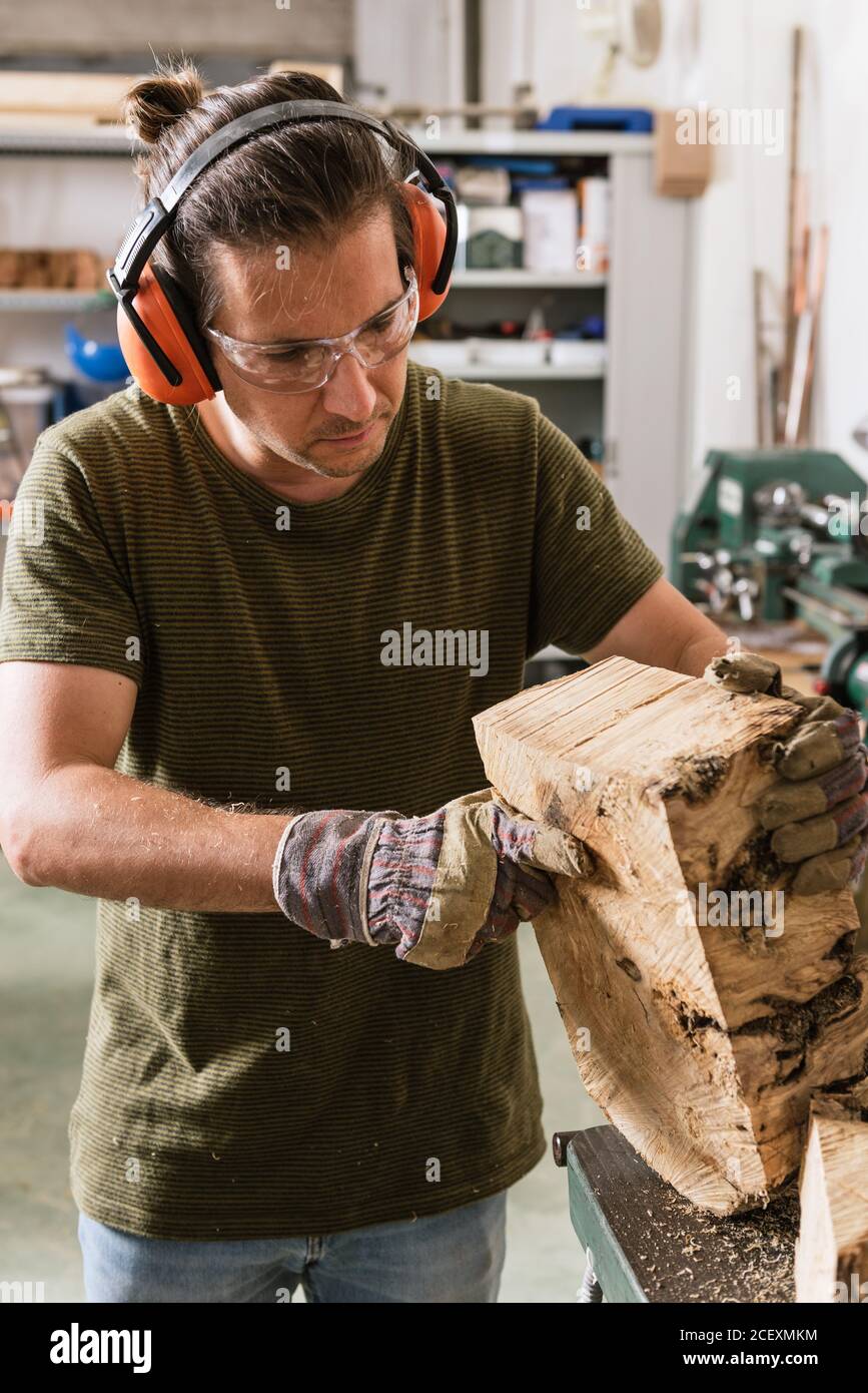 Lavoro di legno maschile concentrato in occhiali protettivi e cuffie  auricolari industriali in piedi al banco da lavoro con legno Foto stock -  Alamy