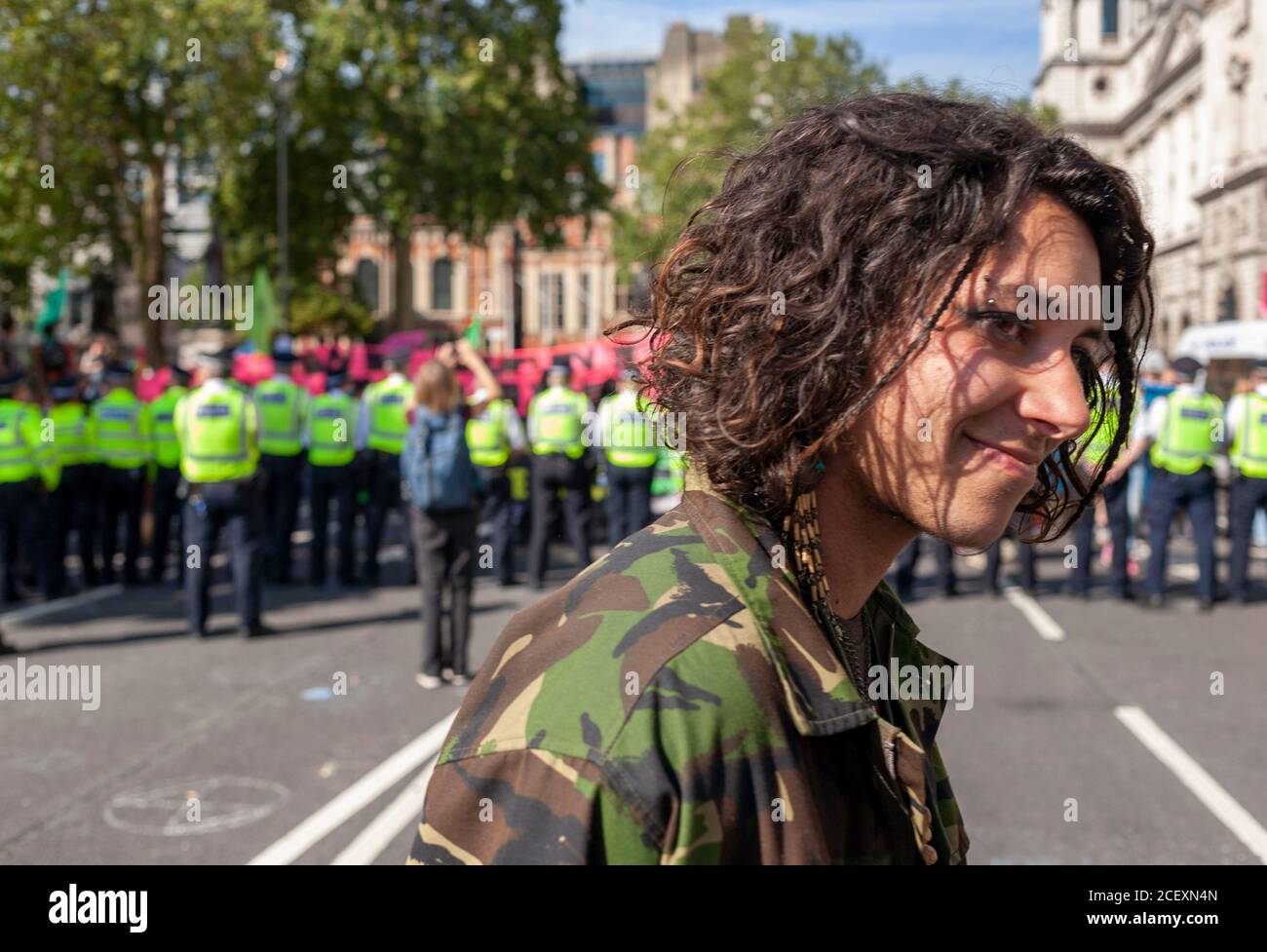 Un giovane sostenitore della ribellione estinzione cammina di fronte a una linea di polizia durante le 2020 manifestazioni fuori dalle Camere del Parlamento britannico. Londra. Foto Stock