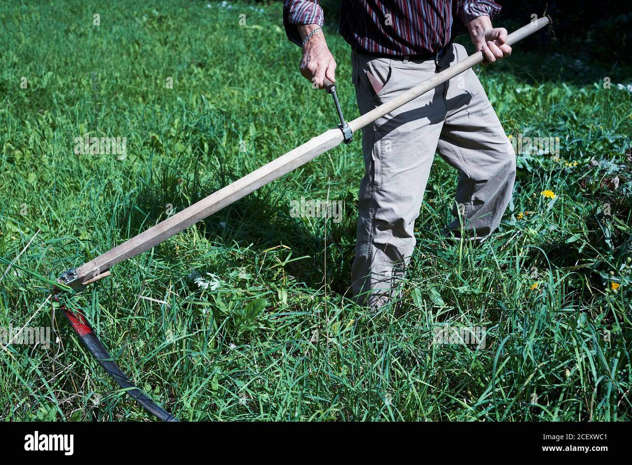 L'uomo che taglia l'erba con una falce. Sfondo, primo piano. Foto Stock