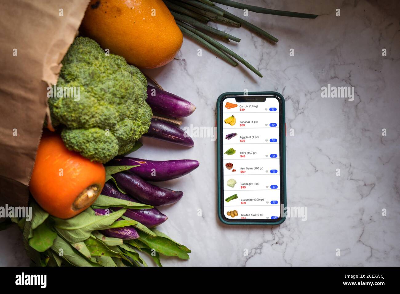 Vista dall'alto di frutta e verdura assortite in sacchetto di carta organizzato sul tavolo con smartphone con app per lo shopping online e consegna Foto Stock