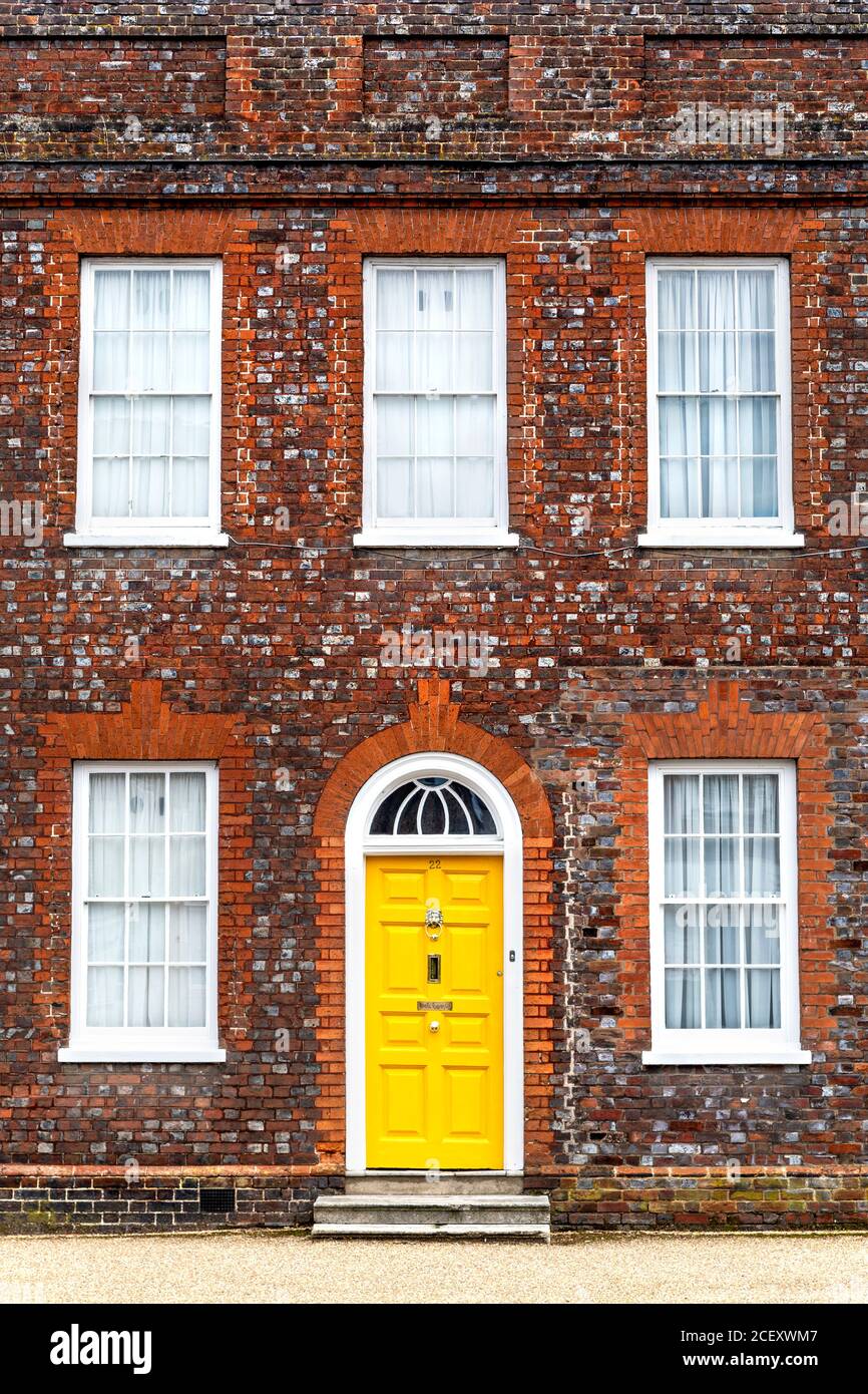 Una porta gialla luminosa in una casa in mattoni rossi georgiani, Baldock, Regno Unito Foto Stock