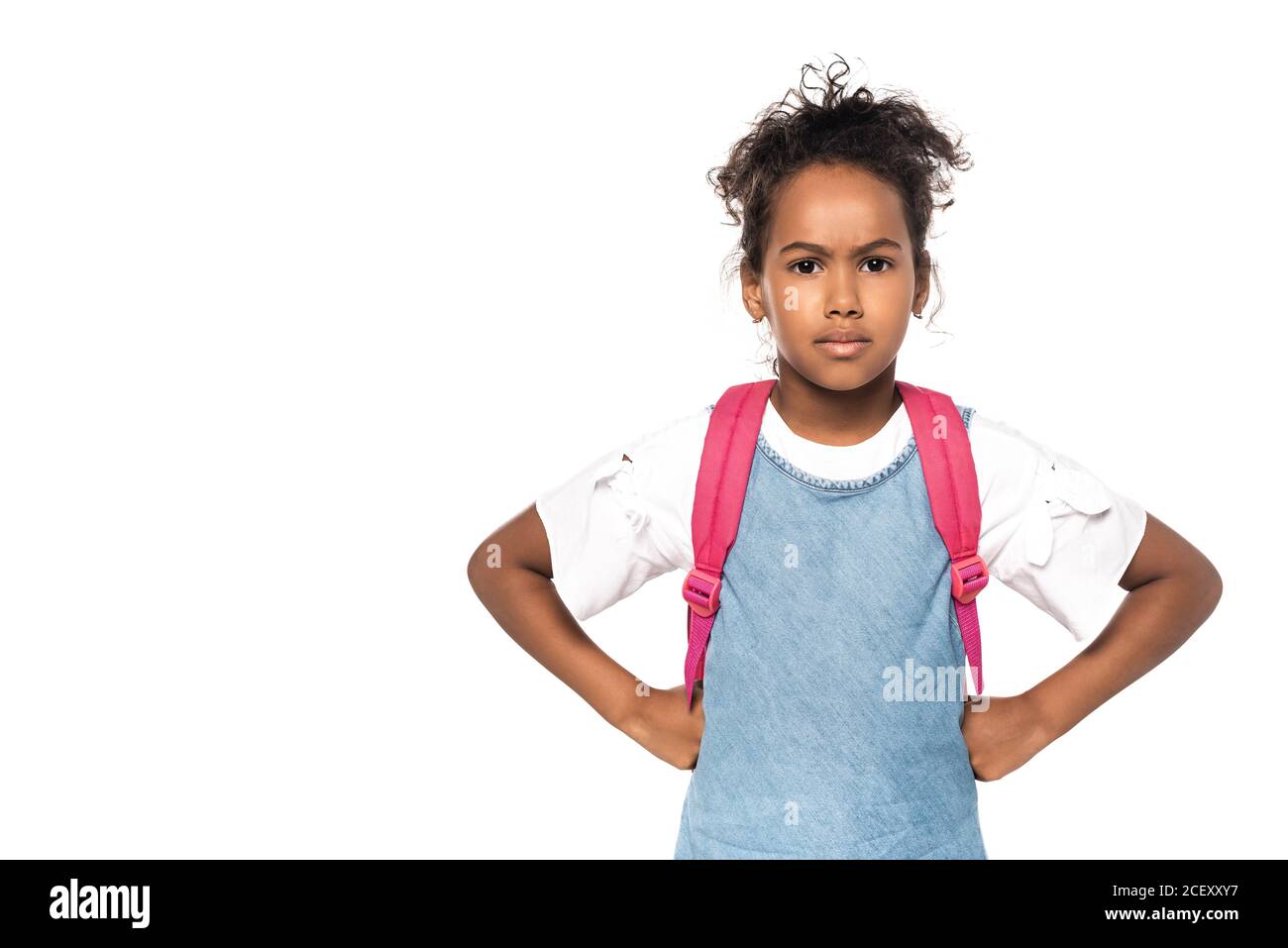 serio aloafroamericano che guarda la macchina fotografica mentre in piedi con mani su fianchi isolati su bianco Foto Stock