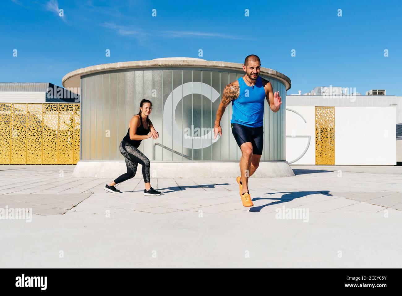 L'atleta maschile focalizzato inizia a correre velocemente durante l'allenamento con la donna pullman personale su strada lastricata Foto Stock
