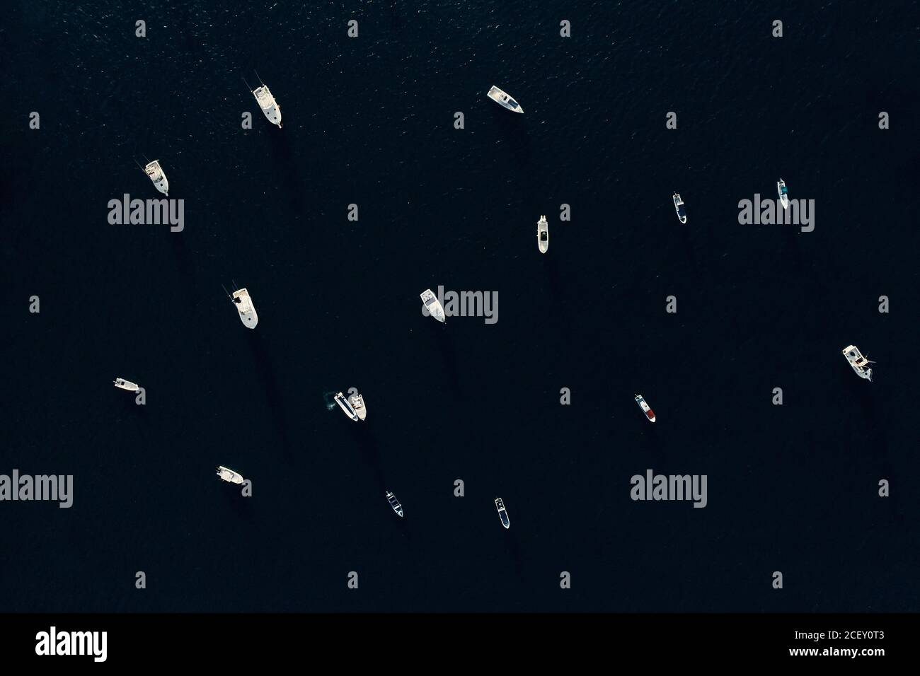Dall'alto di varie barche a motore moderne che galleggiano sulla calma superficie del mare durante la giornata di sole Foto Stock