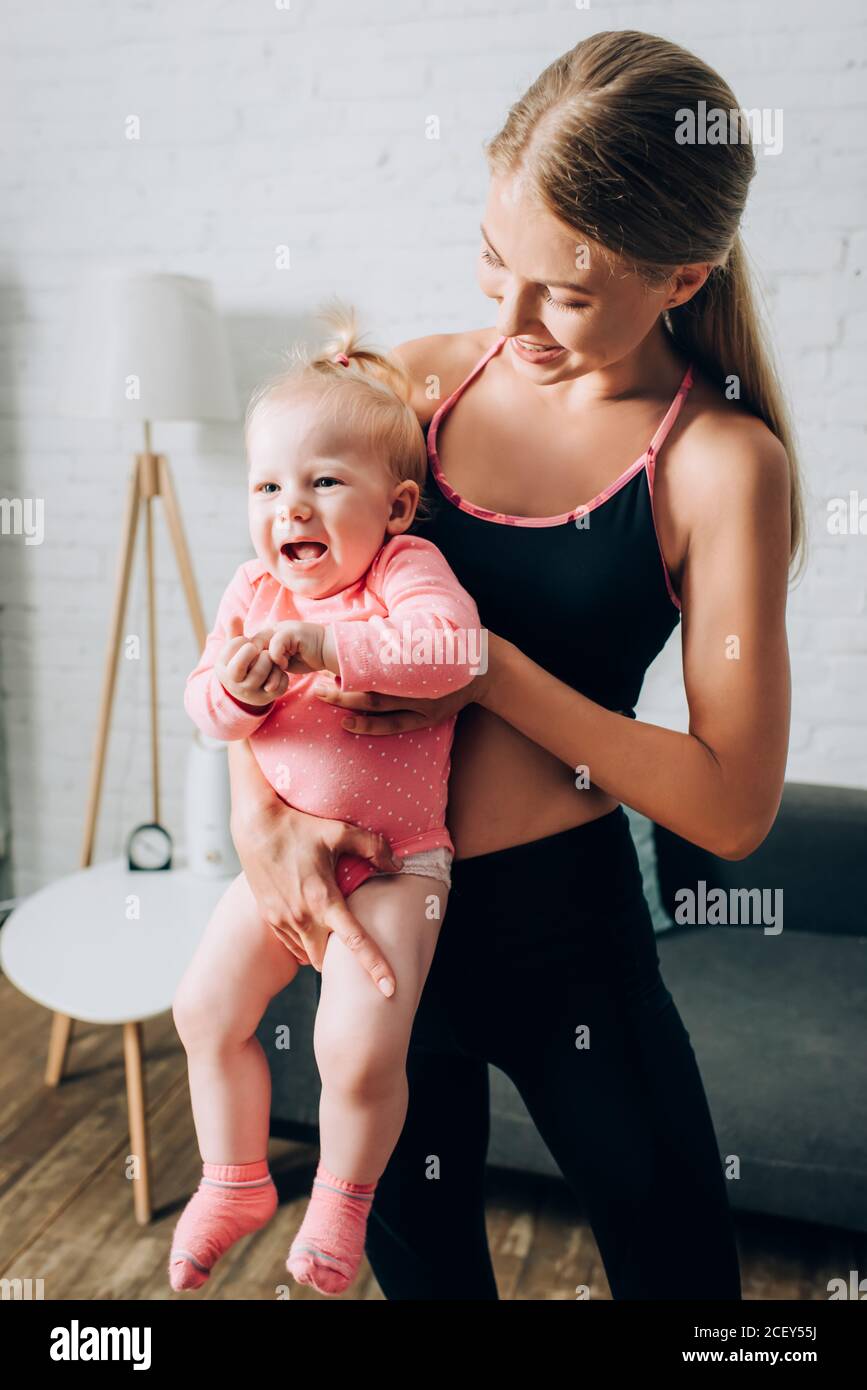 Donna in forma che tiene la figlia del bambino in soggiorno Foto Stock