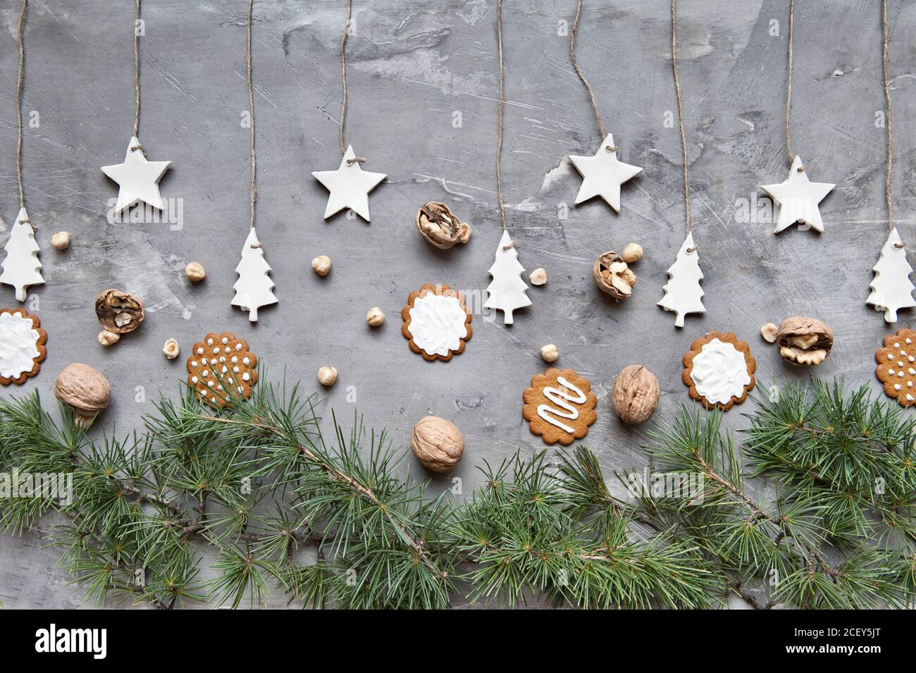 Accordo di Natale invernale con vari biscotti e noci messi con rami di abete verde e decorazioni fatte a mano su sfondo grigio Foto Stock