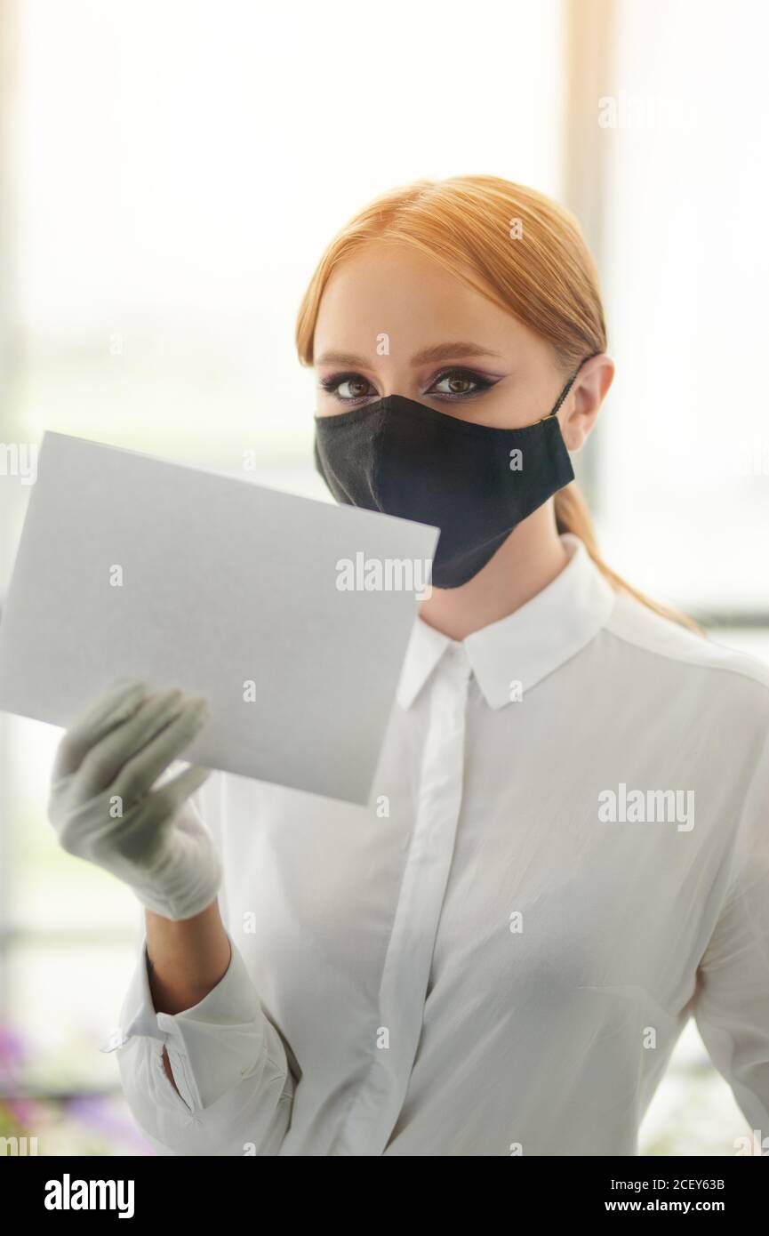 Giovane donna in maschera tenere vuota bacheca di notifica Foto Stock