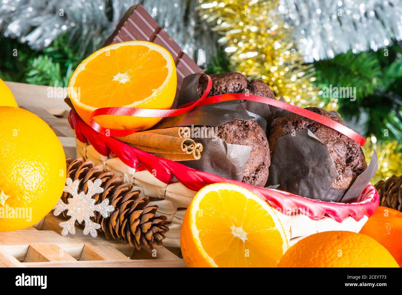Vacanze di Natale ancora in vita con close up muffin, bastoncini di cannella, arance, cioccolato e cono di pino Foto Stock