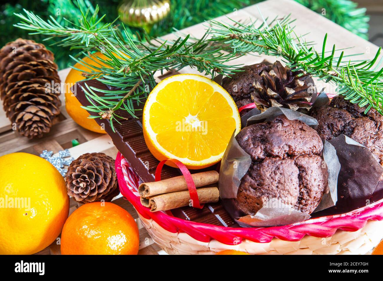 Vacanze di Natale ancora in vita con close up muffin, bastoncini di cannella, arance, cioccolato e cono di pino Foto Stock