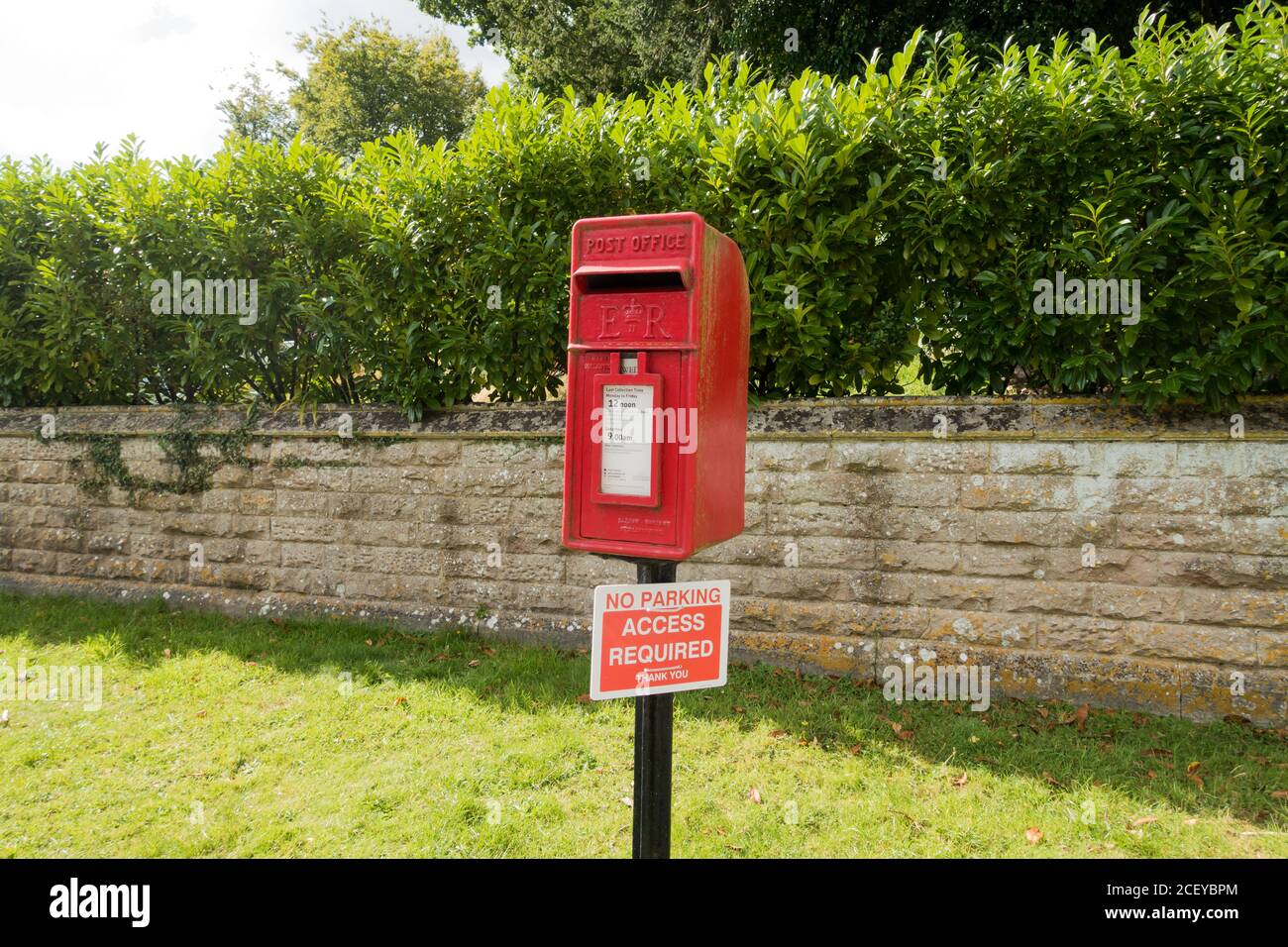 Una casella postale rurale rossa Royal Mail con un avviso 'Nessun parcheggio' 'accesso richiesto'. Witchampton, Dorset, Inghilterra Foto Stock
