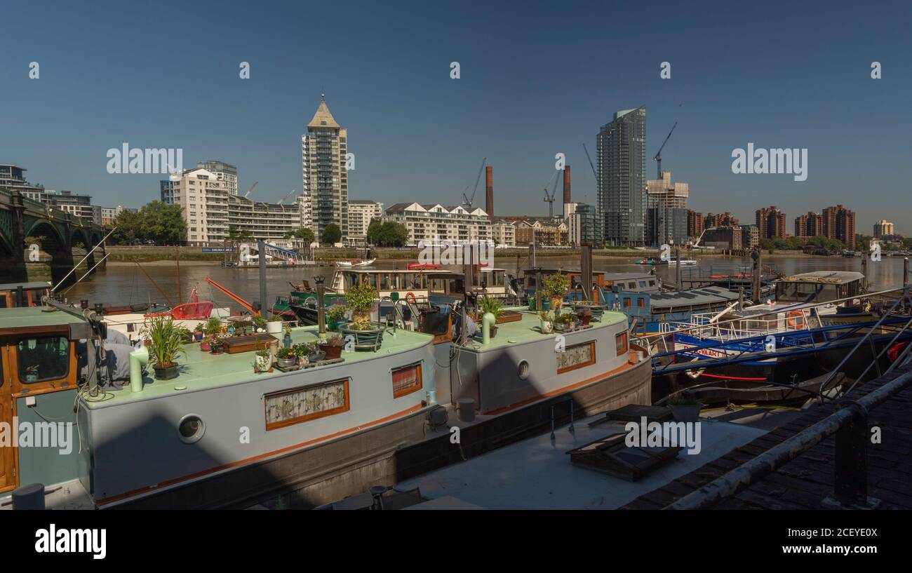 Houseboats si oppone all'architettura di gentrifificazione lungo il fiume Tamigi a Battersea, Greater London, England, United Kingdom, Europe Foto Stock