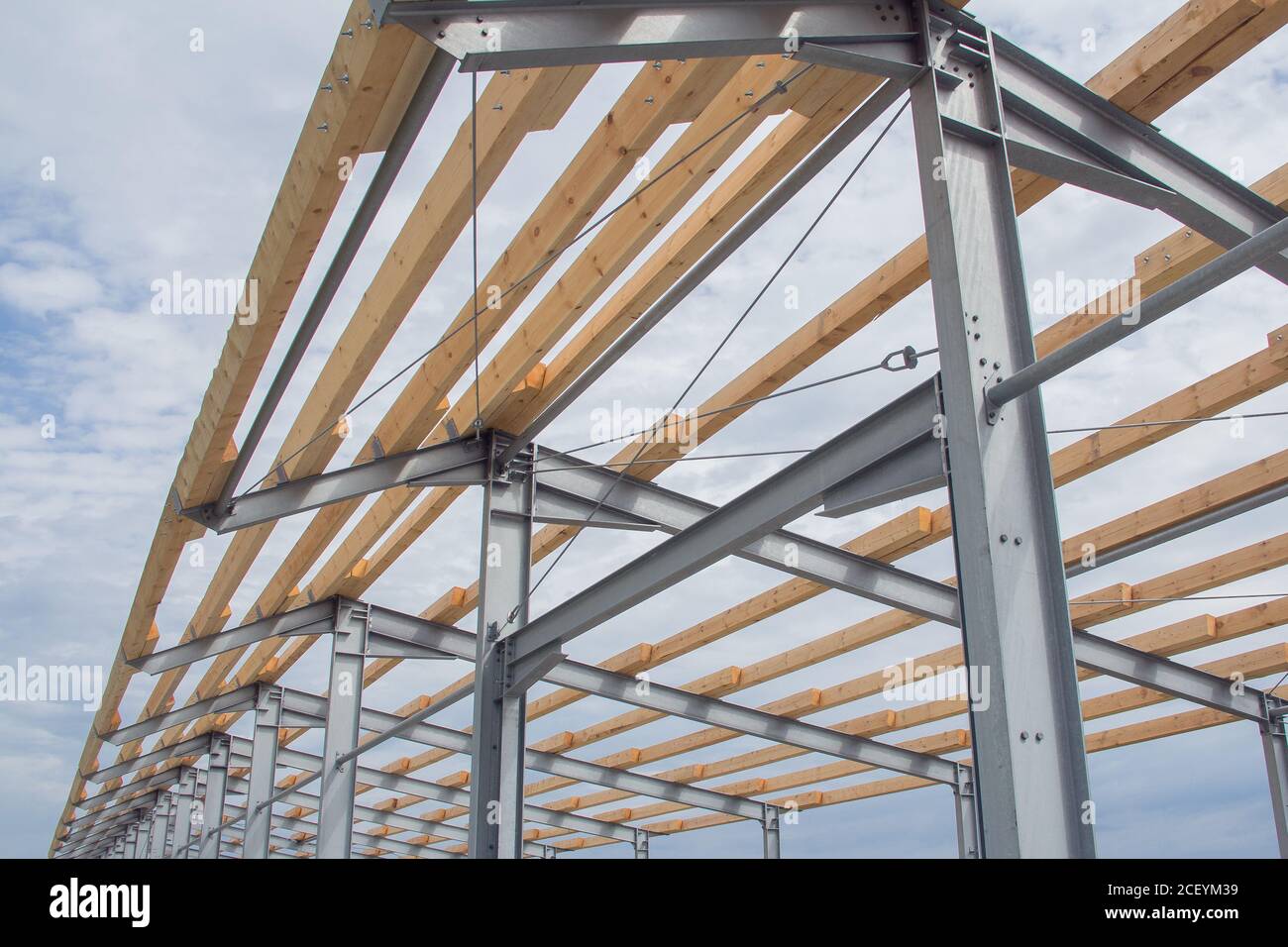 Costruzione di tetti con travi in legno e telai in acciaio. Costruzione agricola di edificio Foto Stock