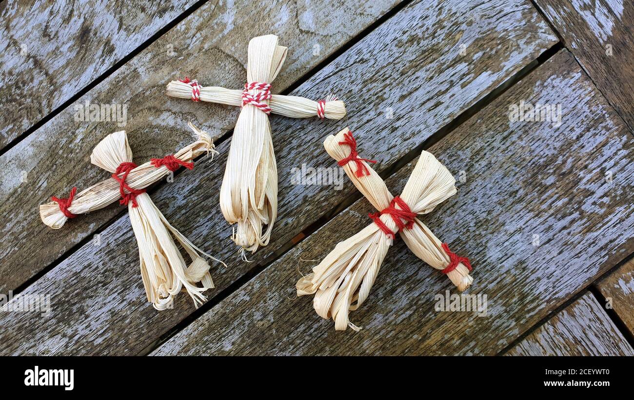Tre bambole di buccia di mais fatte a mano su sfondo di legno, tema di raccolta autunno, fascino di buona fortuna. Foto Stock