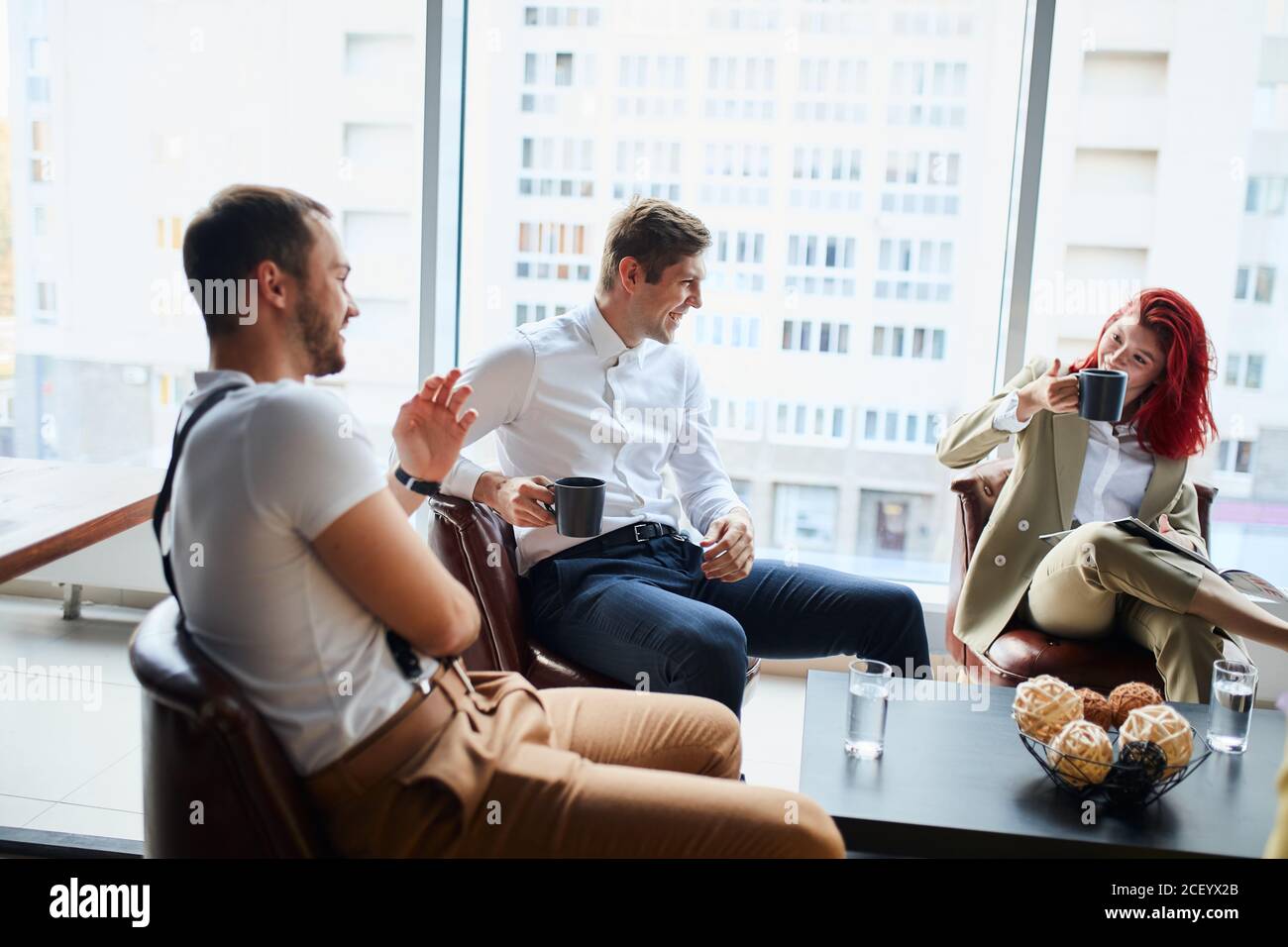 Dirigenti che hanno una discussione amichevole durante la pausa, le idee di affari, la costruzione della strategia di affari mentre si siitng sul tavolo insieme. Background di ufficio Foto Stock