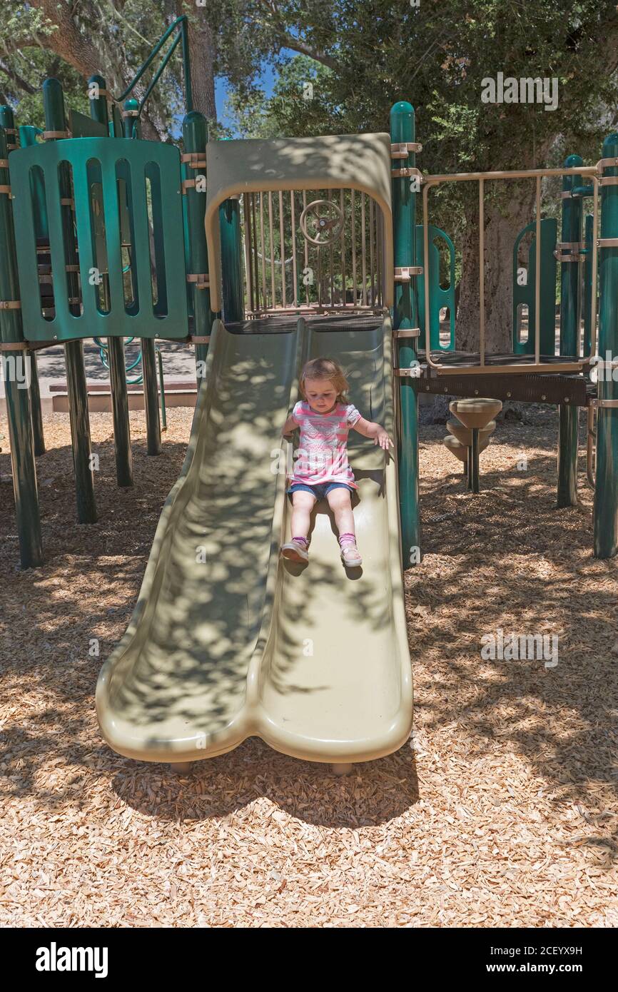 Little Girl giocando su uno scivolo in California Foto Stock