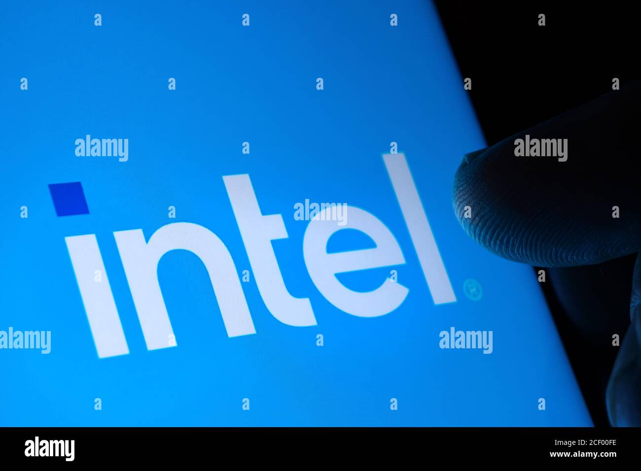 Nuovo logo Intel visualizzato sullo schermo e la punta delle dita sfocata che lo tocca al buio. Intel ha rinominato il proprio logo. Selettivo Foto Stock