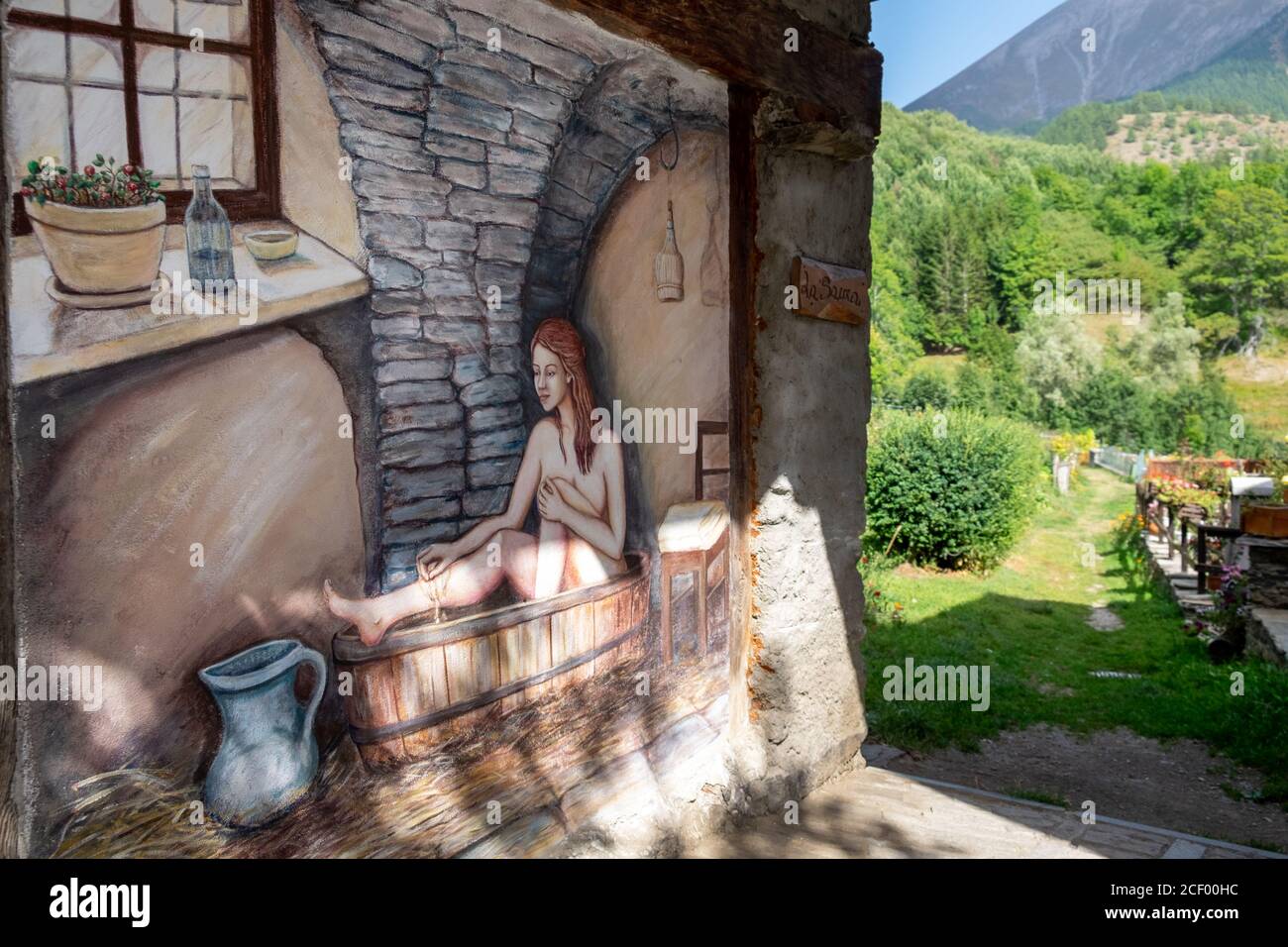 Murale dipinto di una donna che bagna in una vasca da bagno nel piccolo villaggio di Usseaux, Piemonte, Italia Foto Stock