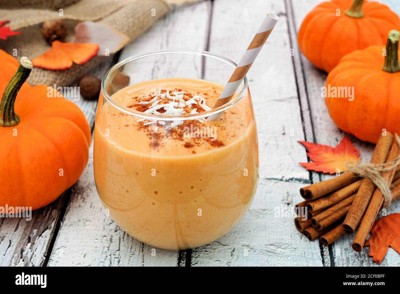 Frullato di zucca autunnale con cocco e cannella, ancora vita su legno bianco Foto Stock