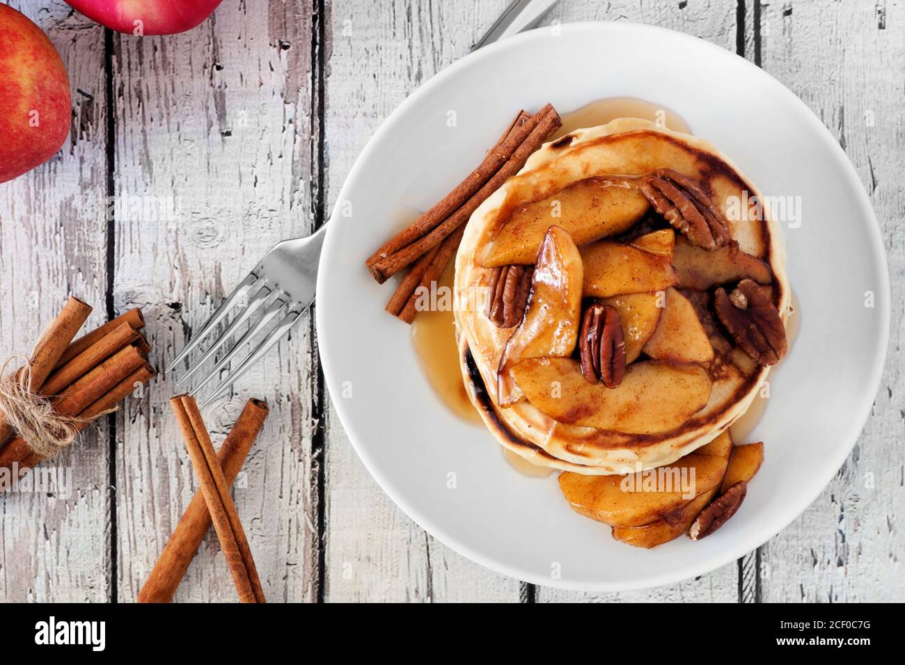 Pezzetto di pancake autunnali con mele, noci pecan e cannella cotte con sciroppo d'acero, vista dall'alto Foto Stock