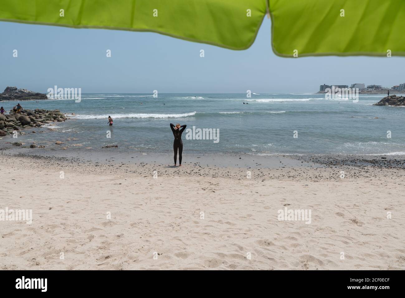 Spiaggia di San Bartolo, Perú. Marzo 2020. Donna che indossa una muta nera prima di entrare nell'oceano. Foto Stock