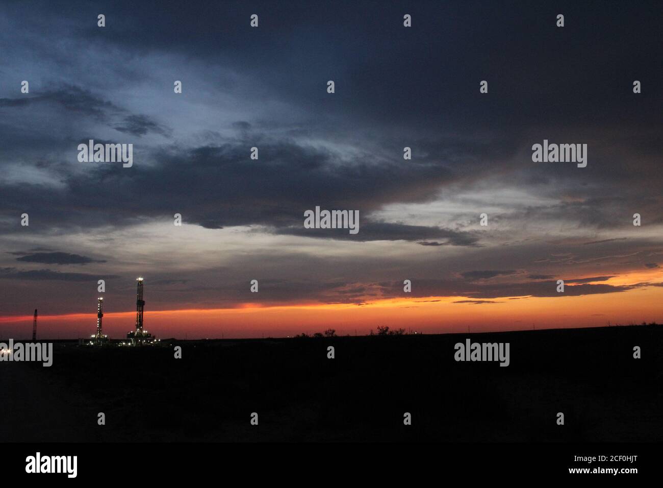 Incredibile vista dei carri di perforazione di petrolio e gas nel bacino Permiano del texas occidentale al tramonto. Foto Stock