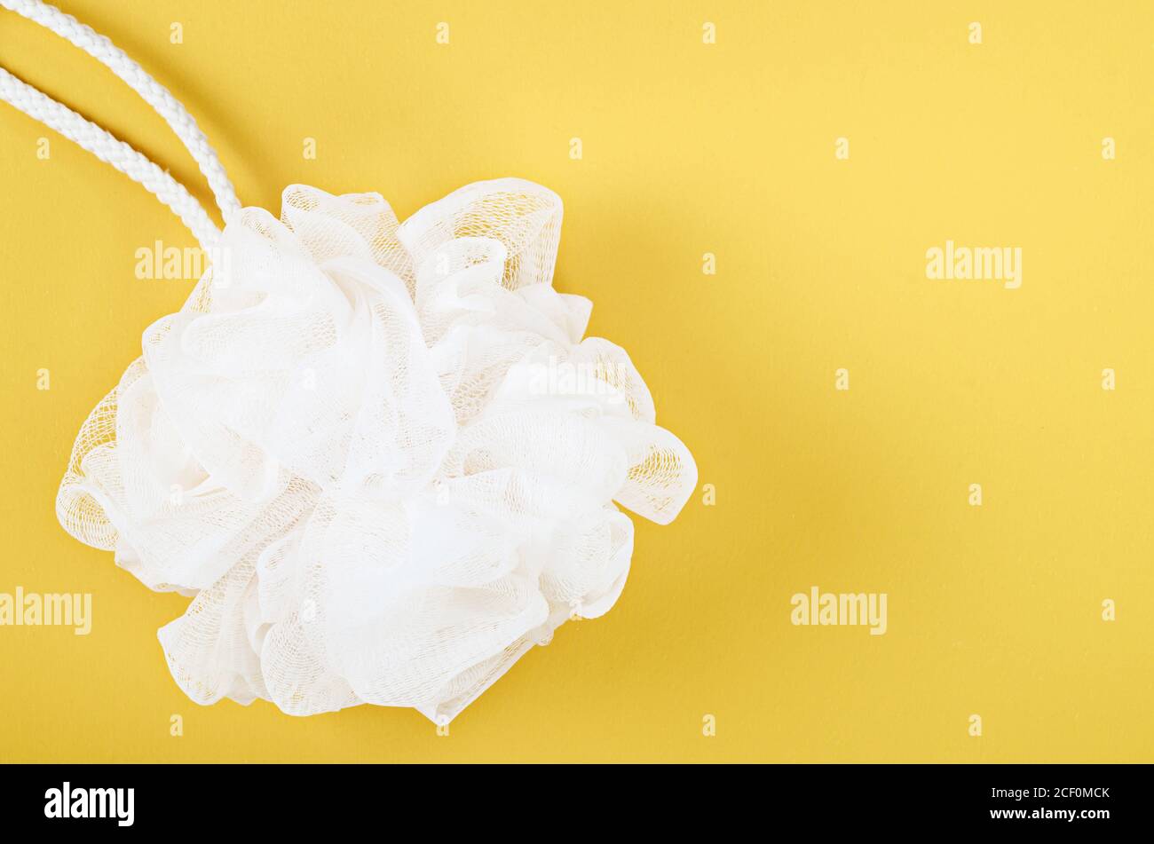 Spugna doccia bianca, scrubber corpo bagno su sfondo giallo. Foto Stock
