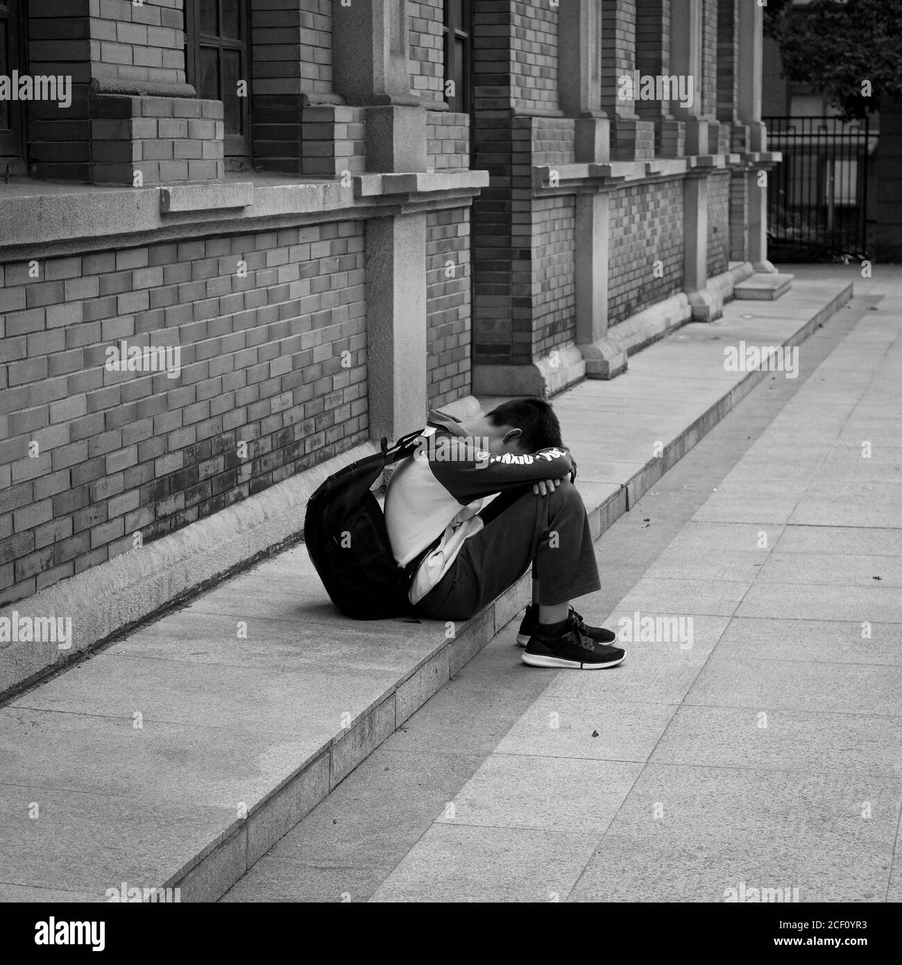 un ragazzo solitario si siede sulla strada Foto Stock