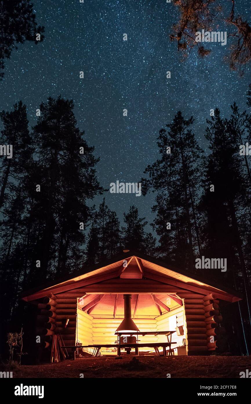 Rifugio in legno e camino con cielo stellato notturno sullo sfondo in Finlandia. Foto Stock