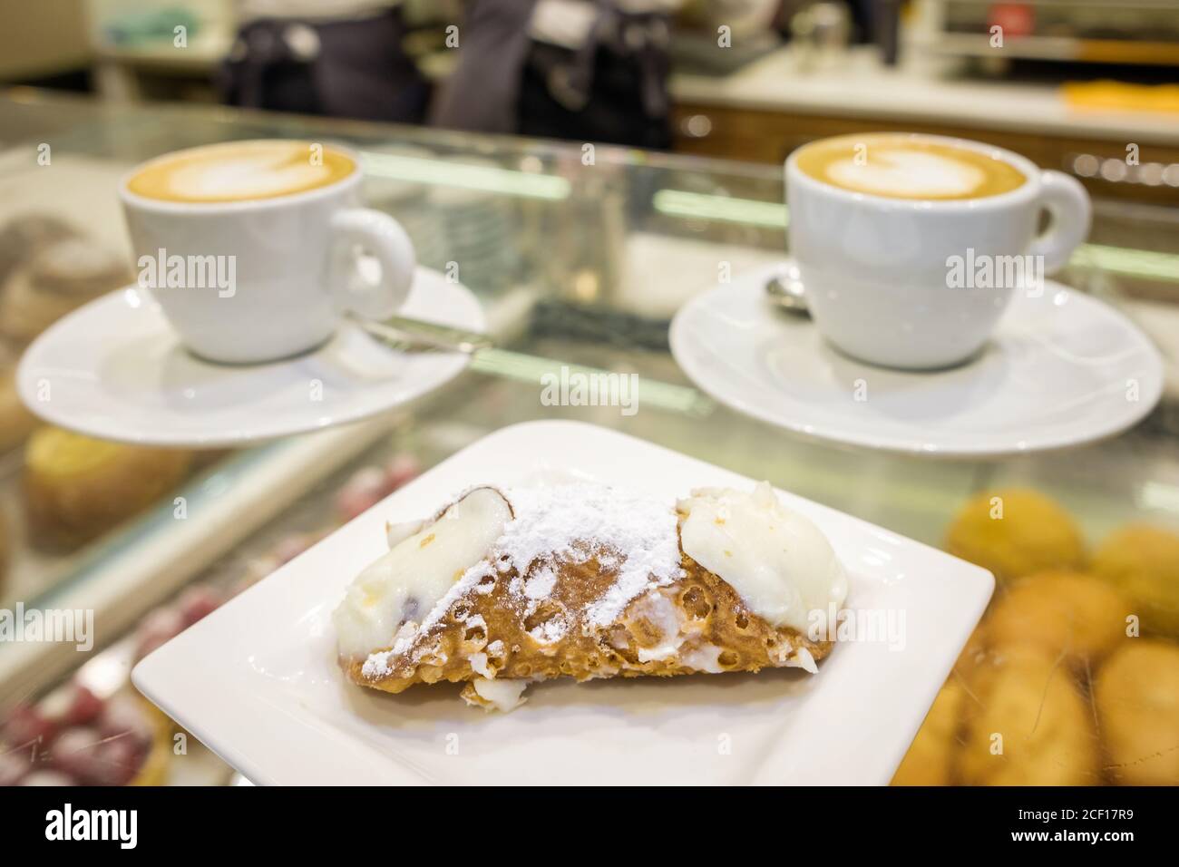 Due tazze di cappuccino e dessert di ricotta cannoli freschi da vicino al bar in Sicilia, Italia. Foto Stock