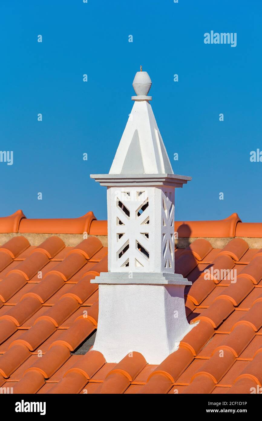 Grazioso camino bianco con tegole arancioni e cielo blu Foto Stock