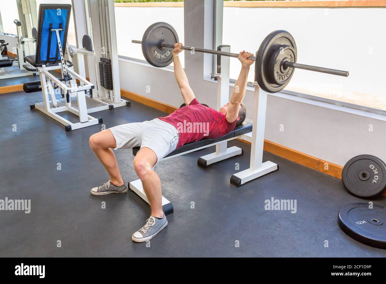 Giovane olandese uomo panca con barbell in sala fitness Foto Stock